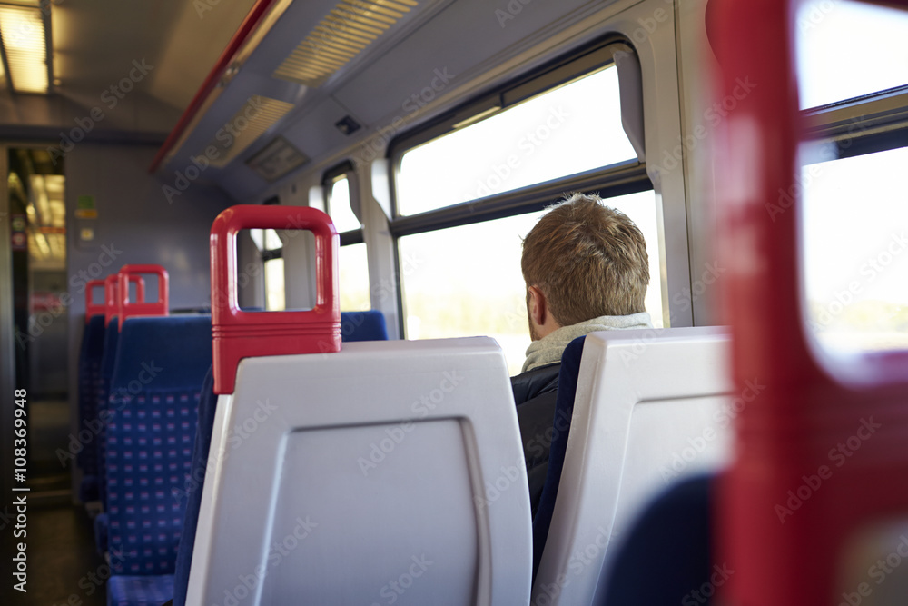 Rear View Of Man Sitting In Train Carriage On Rail Journey Rear View Of Man Sitting In Train Carriage On Rail Journey