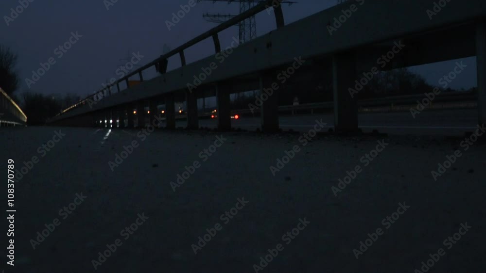 Headlights of passing by cars behind a guardrail - low-angle view Headlights of passing by cars behind a guardrail - low-angle view