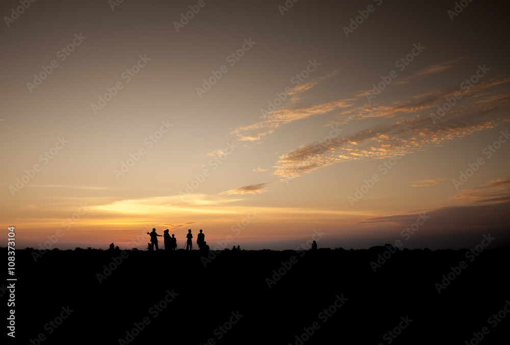 man and woman photographer taking photo on sunset mountain peak