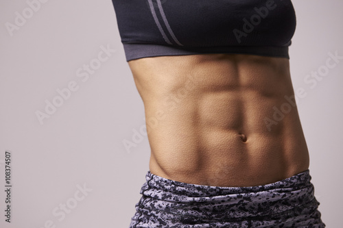 Mid-section crop shot of muscular young woman’s abs