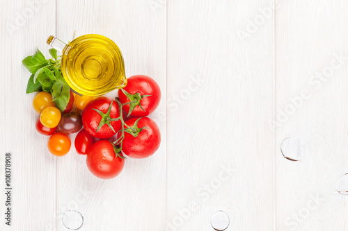 Olive oil, tomatoes, basil on wooden table