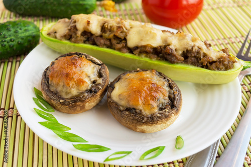 Baked stuffed mushrooms and zucchini on a white plate.