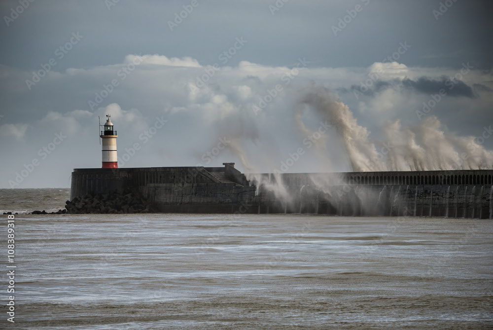 Large sea waves crashing over lighthouse during storm with beaut
