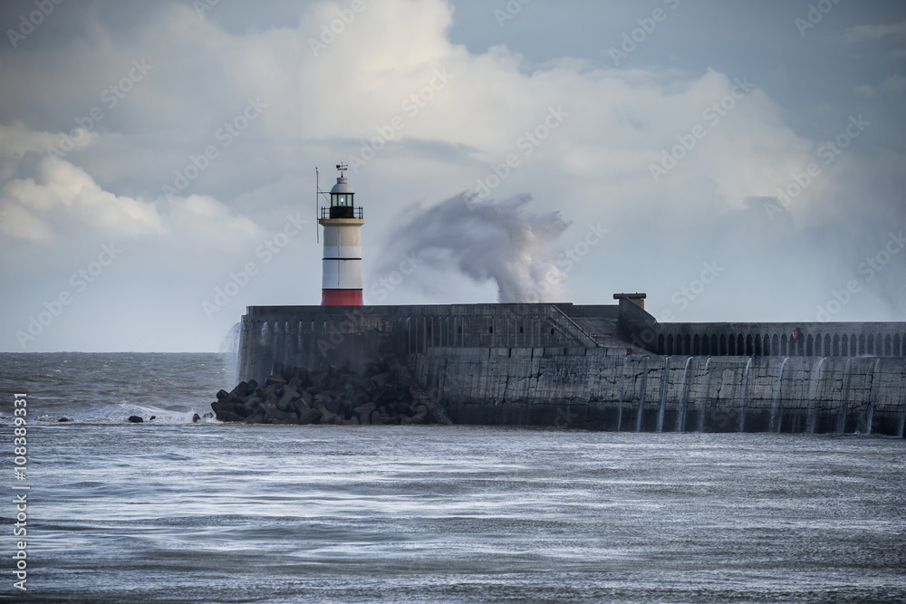 Large sea waves crashing over lighthouse during storm with beaut