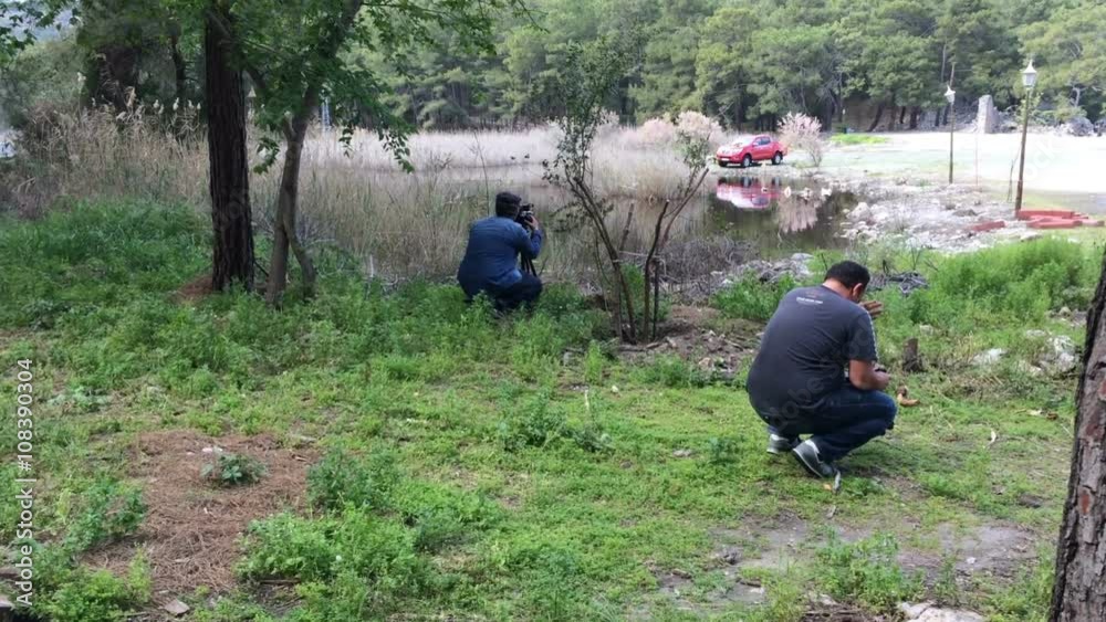 Two men filmed mountain landscape in broad daylight near a pond