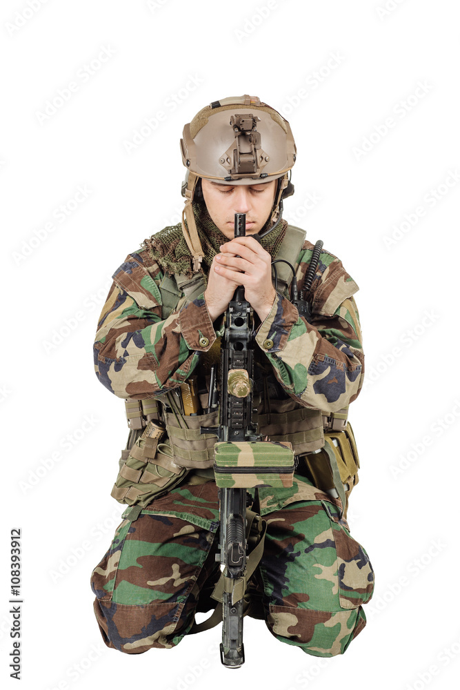 A soldier in camouflage bent over a gun. Praying and sitting with a gun. Image on white background A soldier in camouflage bent over a gun. Praying and sitting with a gun. Image on white background