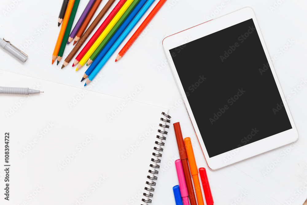 Colored pencils on wood table. Blank notebook and tablet Colored pencils on wood table. Blank notebook and tablet