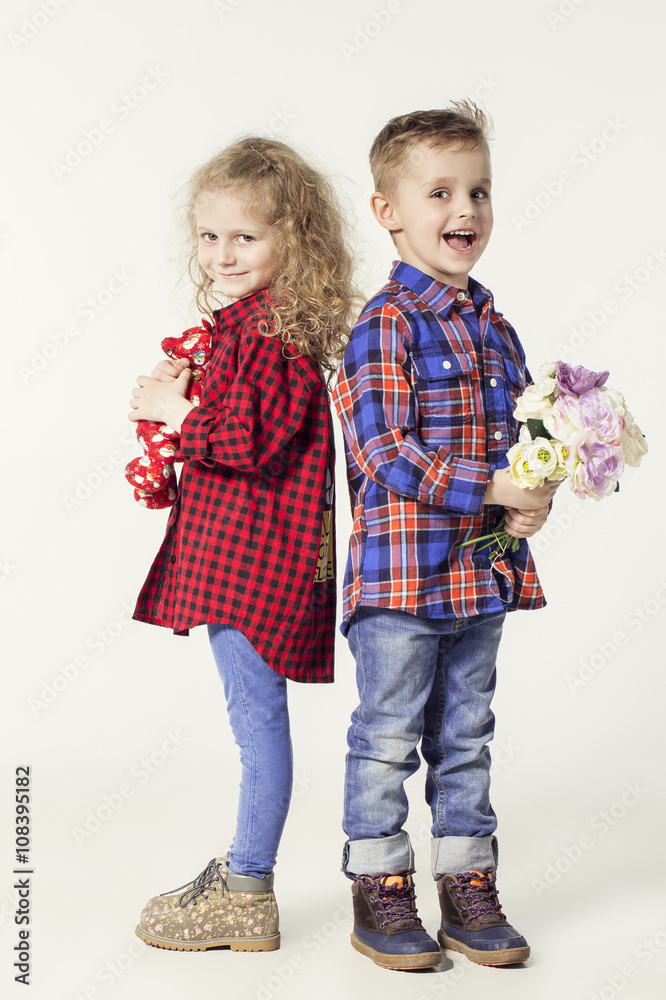 Funny lovely children. fashionable little boy and girl in jeans and plaid  shirts. little boy gives flowers to girl. stylish kids in casual shoes.  fashion children Stock Photo | Adobe Stock