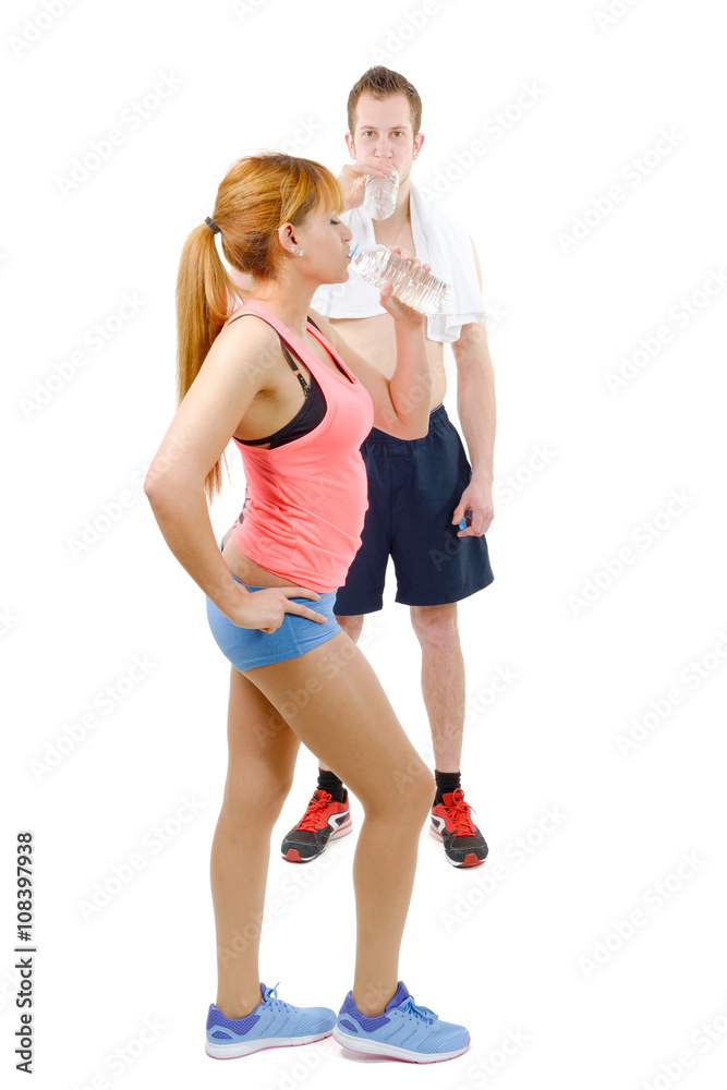 Man and woman at gym in fitness attire holding water bottles Man and woman at gym in fitness attire holding water bottles