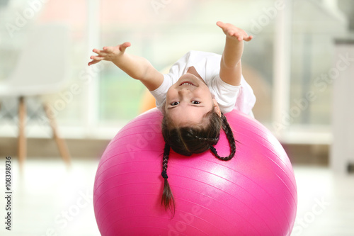 Little cute girl doing exercises with ball indoor