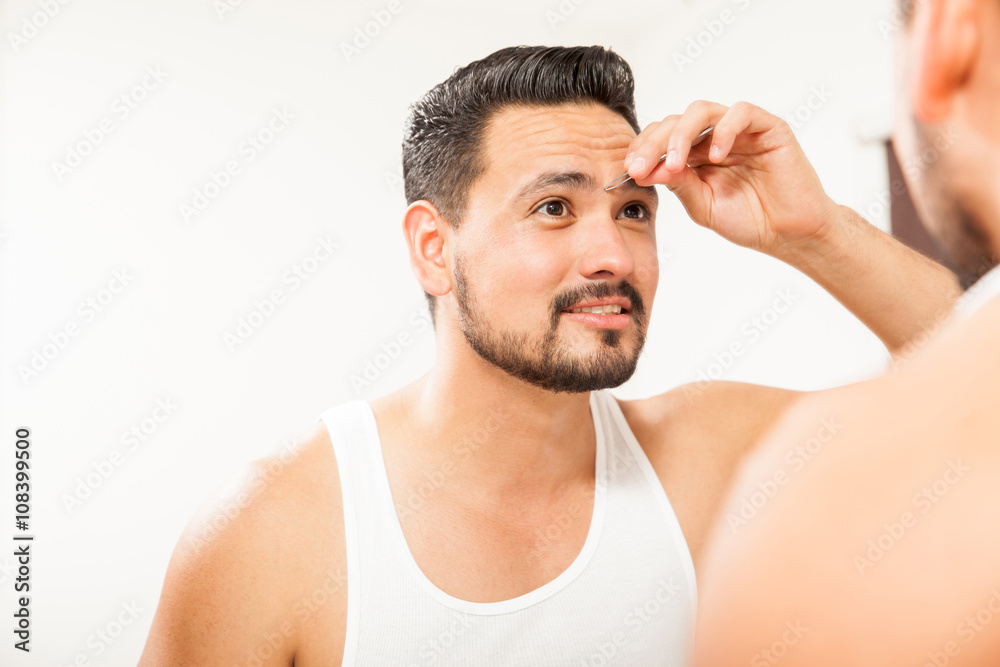 Man plucking his eyebrows in the bathroom