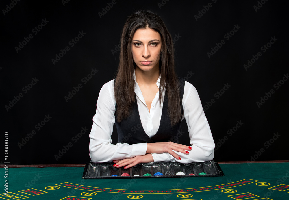 The beautiful girl, dealer, behind a table for poker The beautiful girl, dealer, behind a table for poker