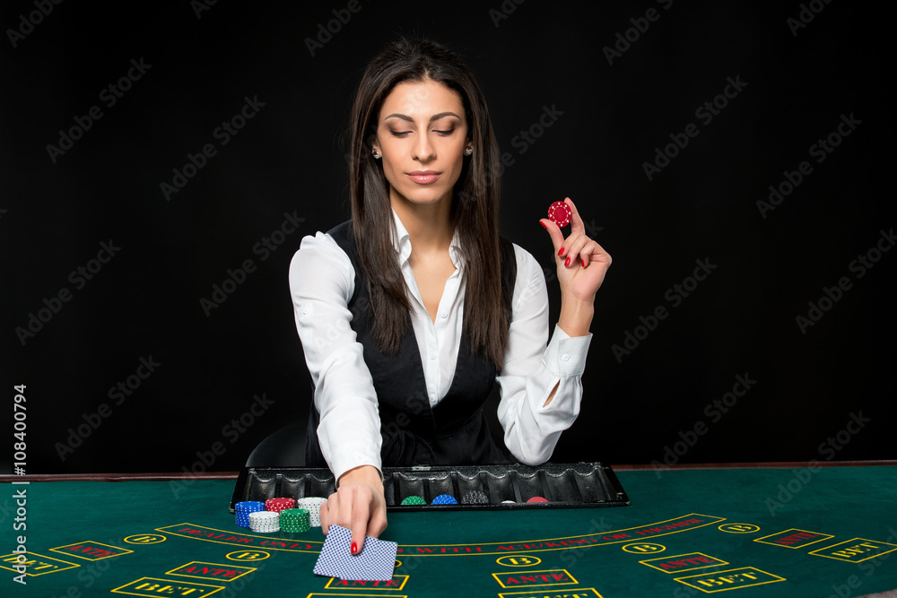 The beautiful girl, dealer, behind a table for poker