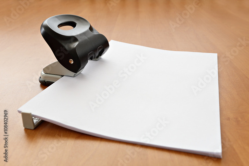 Hole puncher with paper on the office table photo