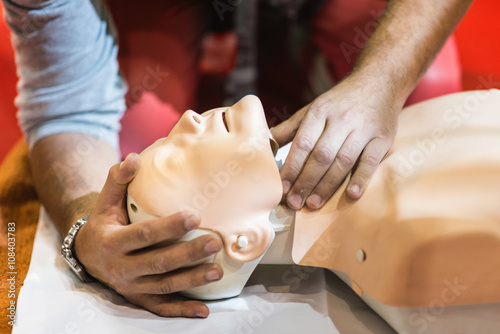 CPR training. Paramedic tilting dummy doll head backwards, checking airways photo