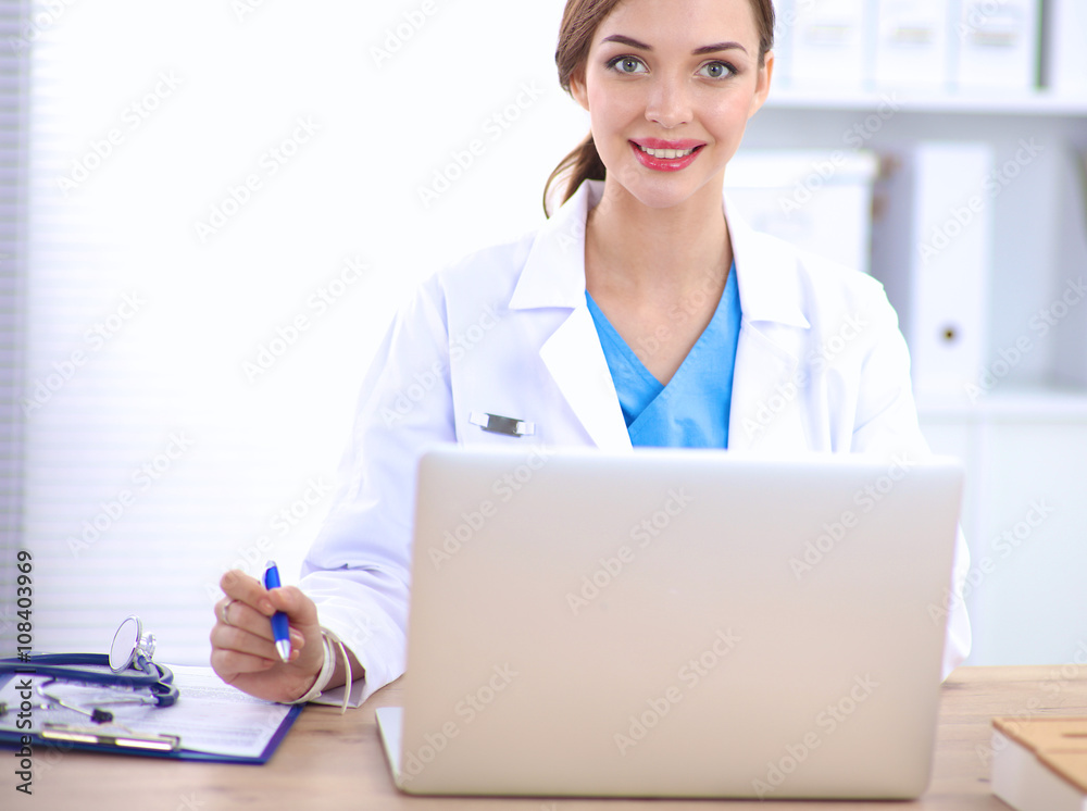 Female doctor sitting on the desk and working a laptop Female doctor sitting on the desk and working a laptop