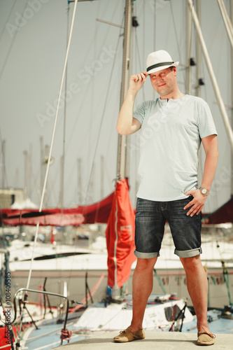 Handsome fashion man on pier in port with yachts.