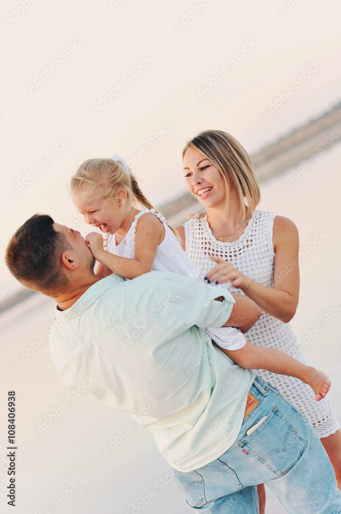 Fototapeta premium Родители играют со своей дочерью летом на пляже