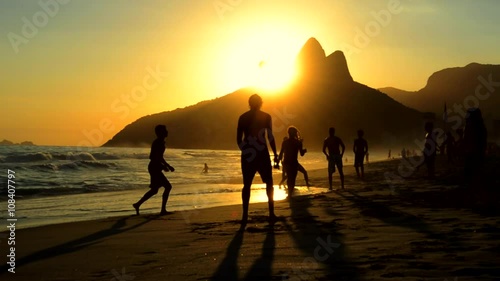 Silhouettes of Carioca Brazilians playing altinho keepy uppy beach football at sunset on Ipanema Beach Rio de Janeiro Brazil