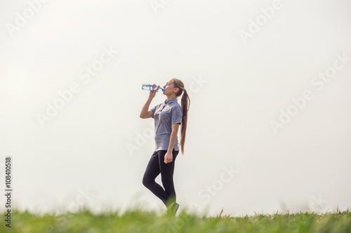 Healthy and Sporty Young Woman Drinking Water from the bottle. Doing Sport Outdoor