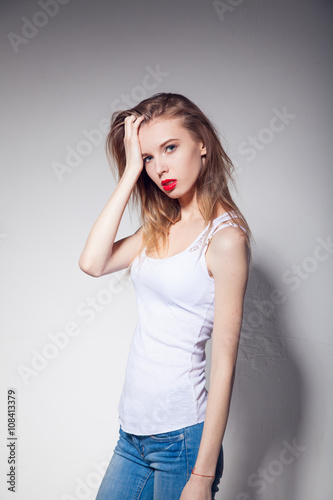 Funny girl in white T-shirt and denim over gray background
