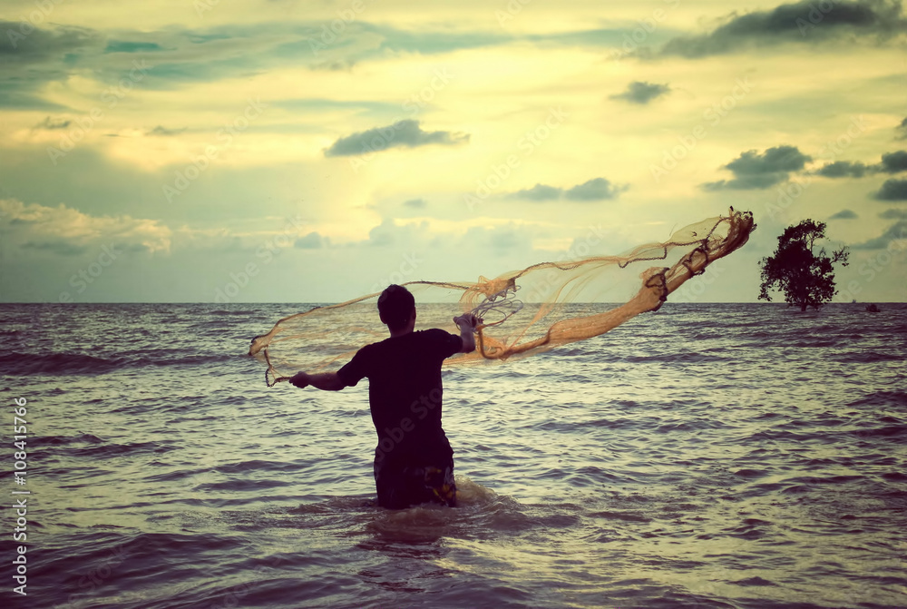 retro look image of a man throwing fishing net with sunset background Stock  Photo