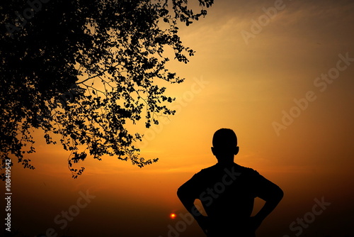 silhouette of a boy watching at sunset, happy enjoying moment, success concept