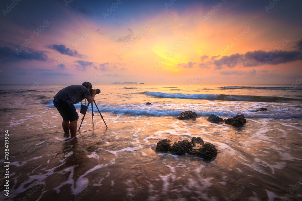 Silhouette of a photographer with dramatic waves at sunrise