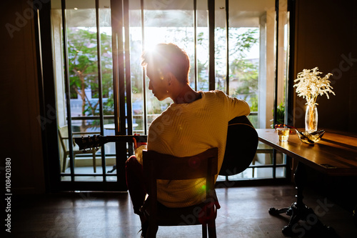asian artist man play guitar in cafe sunlight