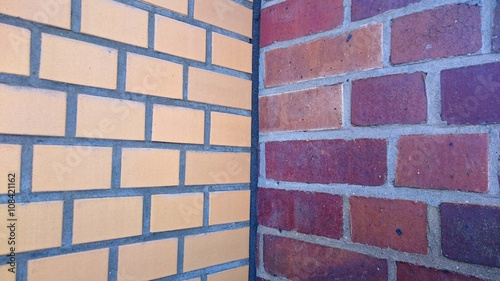 two adjacent brick walls with different patterns and colors meeting in the corner