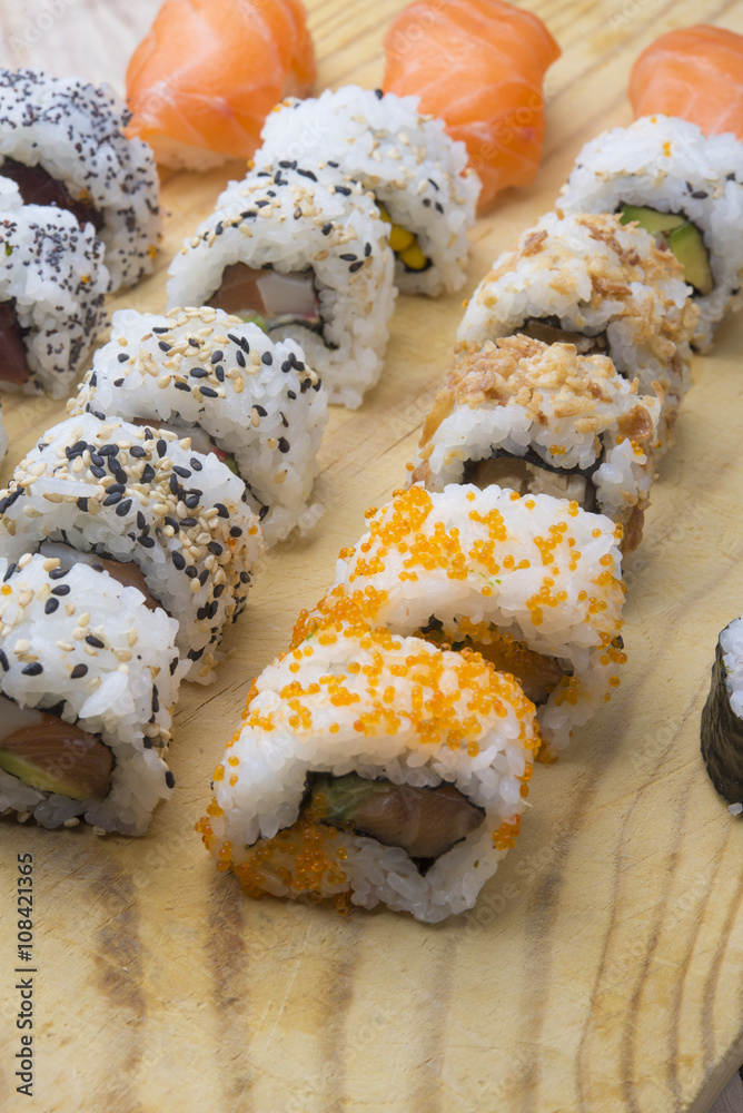 Different Sushi rolls,wasabi and ginger on a plate on wooden bac Different Sushi rolls,wasabi and ginger on a plate on wooden bac