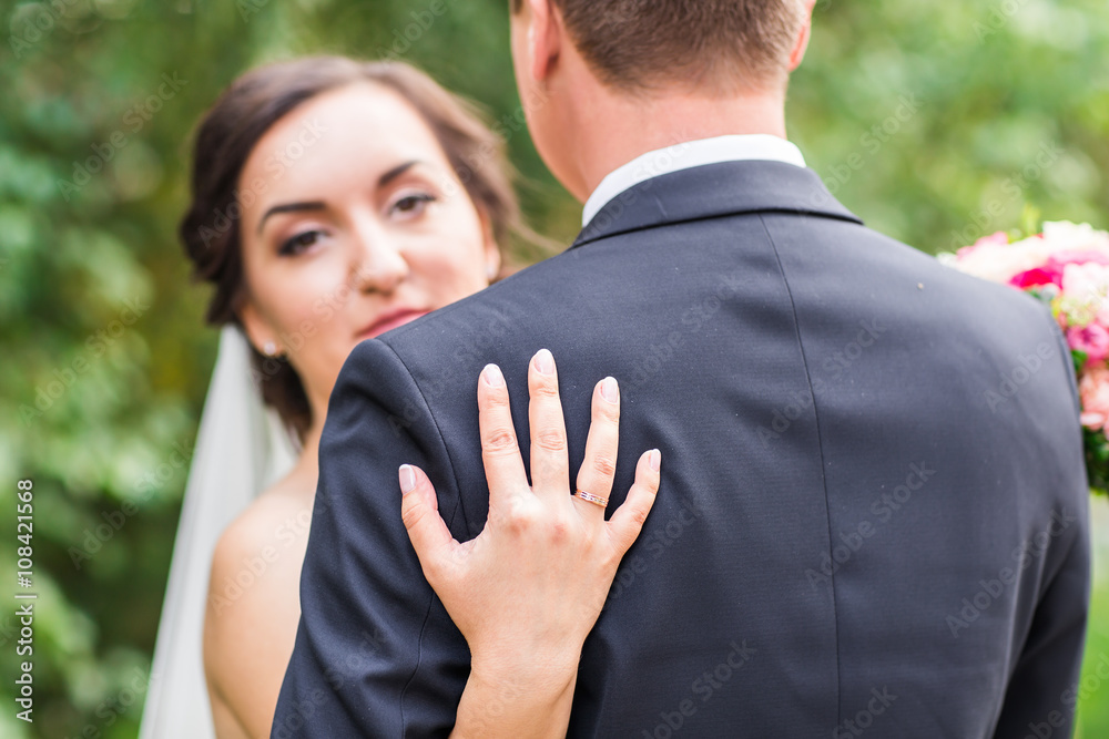 wedding couple hugging, the bride holding a bouquet of flowers, groom embracing her outdoors wedding couple hugging, the bride holding a bouquet of flowers, groom embracing her outdoors