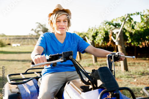 Boy riding farm truck in vineyard
