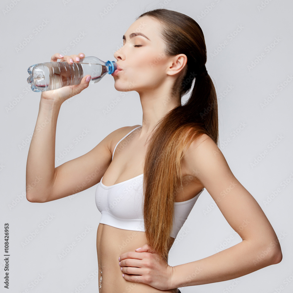sporty woman over gray background drinking water sporty woman over gray background drinking water