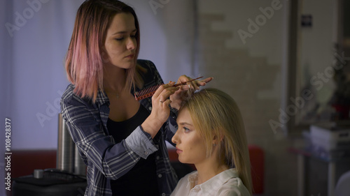 Stylish master hairstyle with pink hair. hairstyle for the attractive blonde in a beauty salon.