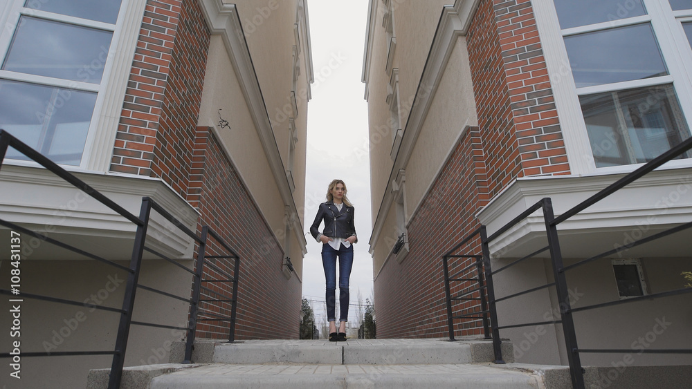 Beautiful thoughtful blond woman stands between two houses. wide angle Beautiful thoughtful blond woman stands between two houses. wide angle