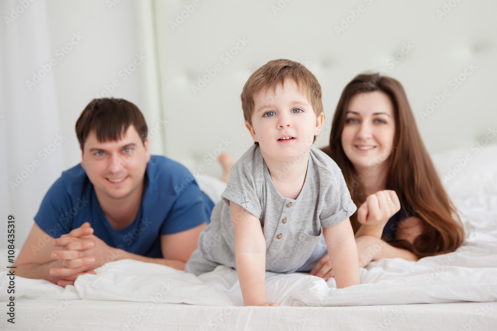 little boy and parents On Parents Bed Wearing Pajamas little boy and parents On Parents Bed Wearing Pajamas