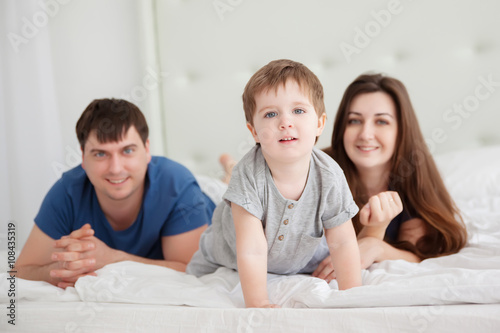 little boy and parents On Parents Bed Wearing Pajamas