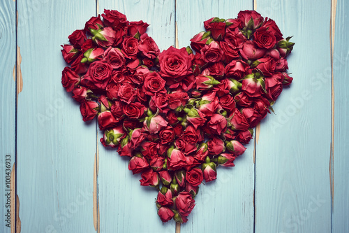 Heart shape of roses on wooden background