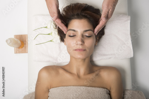 Massaggio al viso di una donna distesa su un lettino di un centro benessere.
