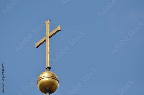 Ein goldenes Kreuz vor blauen Himmel photo