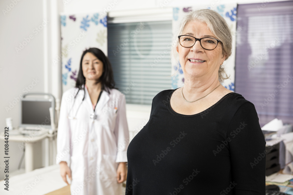 Smiling Senior Patient Standing With Doctor In Background Smiling Senior Patient Standing With Doctor In Background