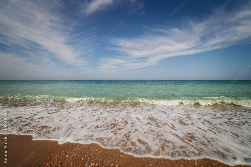 Fototapeta premium Oceanside under blue sky with clouds