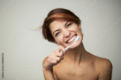 ritratto di ragazza con lo spazzolino simula il lavaggio dei denti- sfondo grigio photo