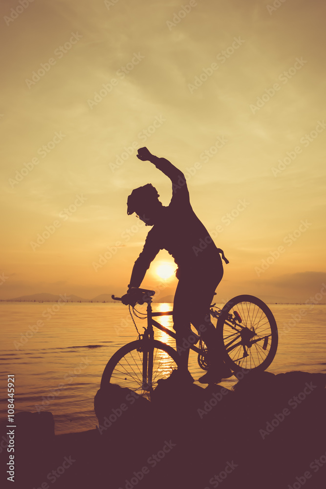 Fototapeta premium Healthy lifestyle. Silhouette of bicyclist riding the bike at seaside.