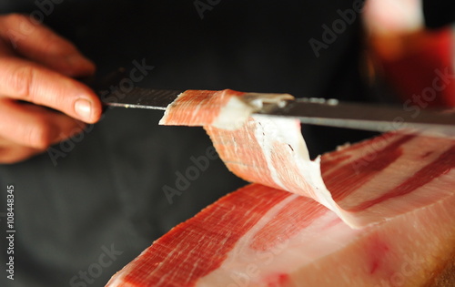 Slicing of italian dry-cured ham prosciutto. Toned image. Selective focus point photo