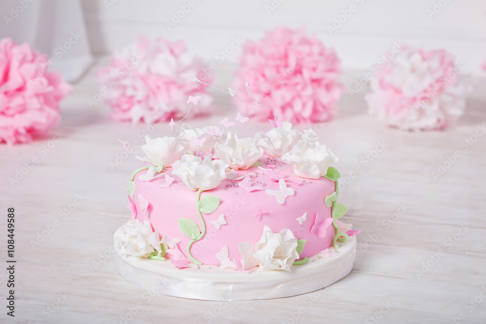Festive cake with flowers and butterflies on a white wooden tabl