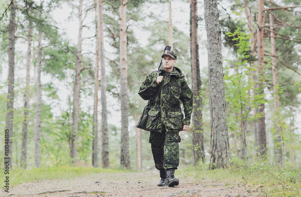 young soldier or hunter with gun in forest