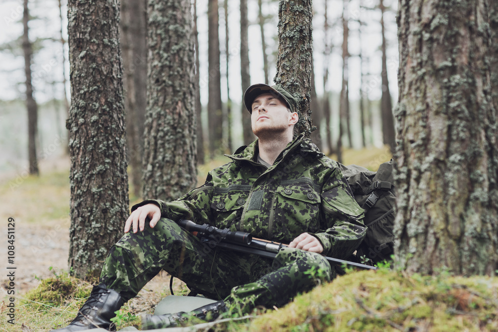 Fototapeta premium soldier or hunter with gun sleeping in forest