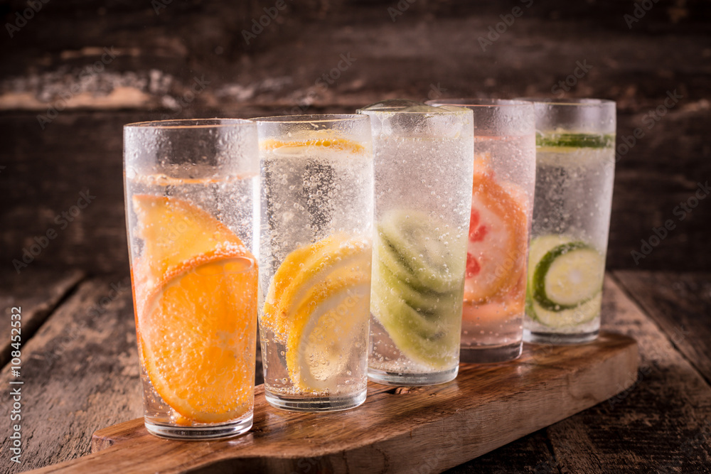 Fototapeta premium Vitamin water with fruits, refreshment cold drink on wooden background